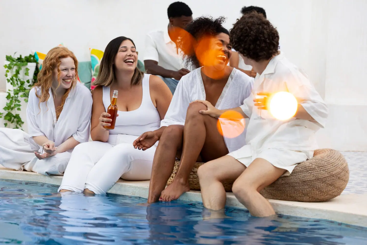 Groupe d'amis en tenue blanche au bord d'une piscine lors d'une soirée d'été