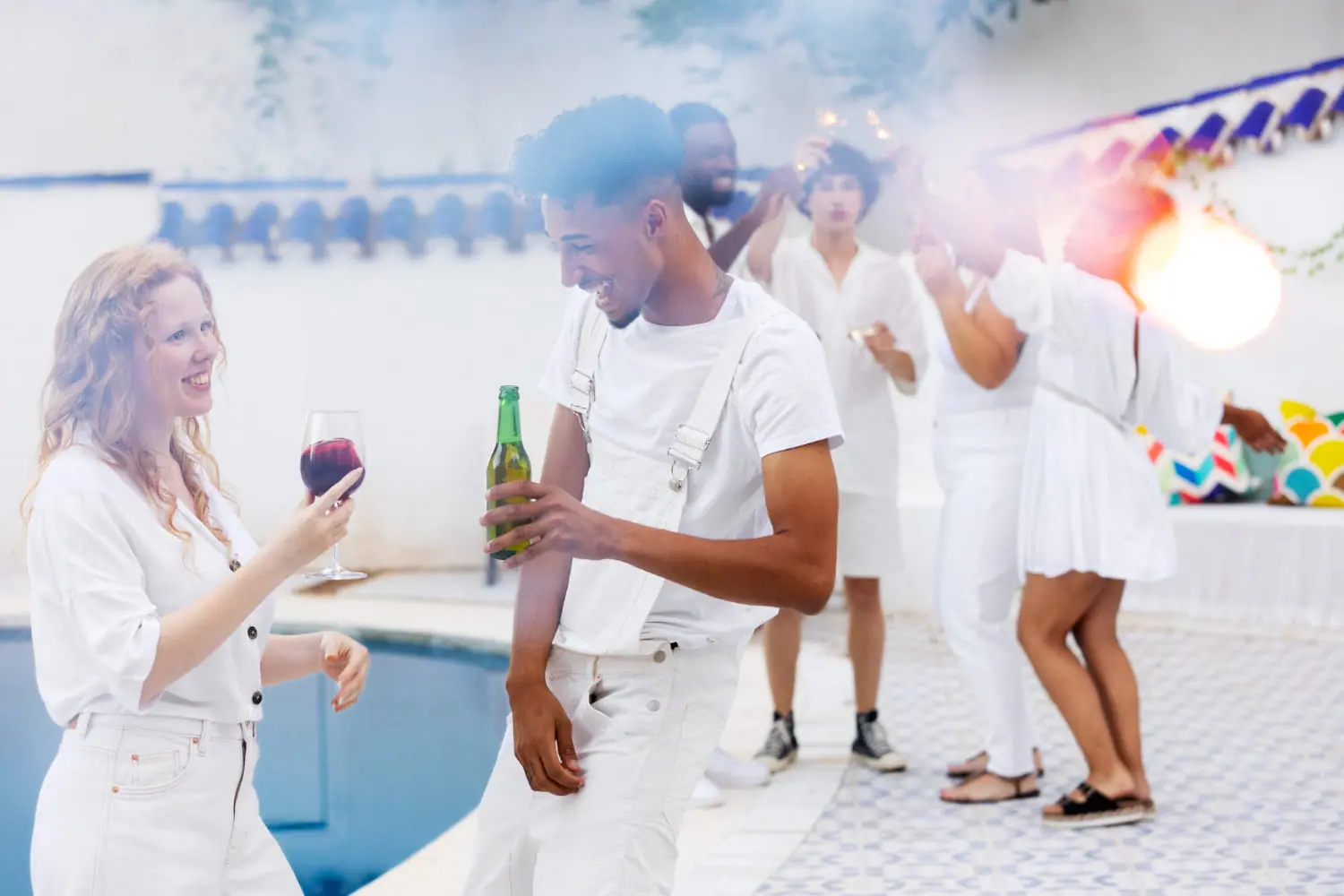 Invités vêtus de blanc dansant au bord d'une piscine lors d'une soirée privée